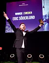 Eric Söderlund håller upp ett pris på scenen framför en skärm med texten World Class.